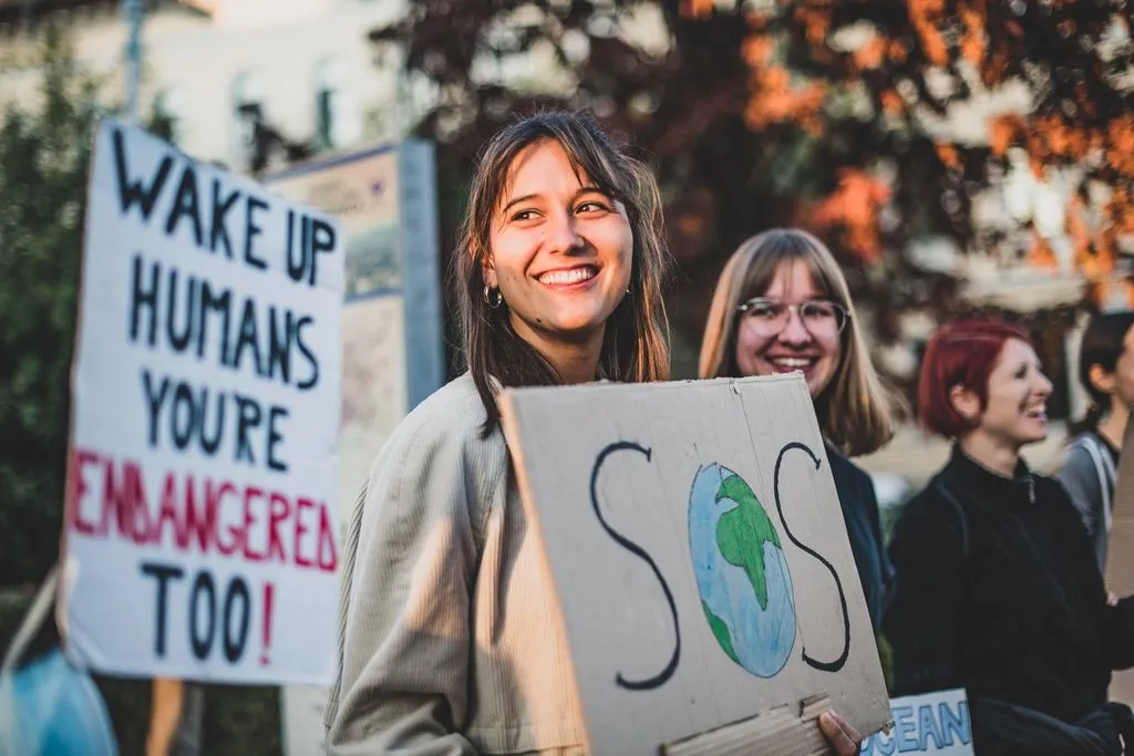 Junge Frau hält ein Protestschild und lächelt