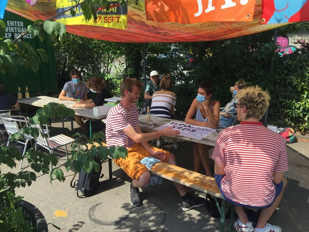 Eine Gruppe von Menschen sitzt draussen an einem Tisch