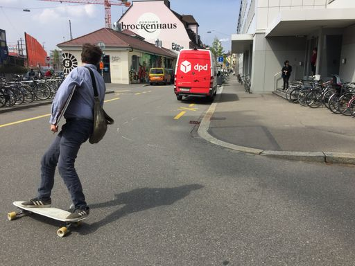 Mann mit Tasche fährt mit Rollbrett auf Strasse