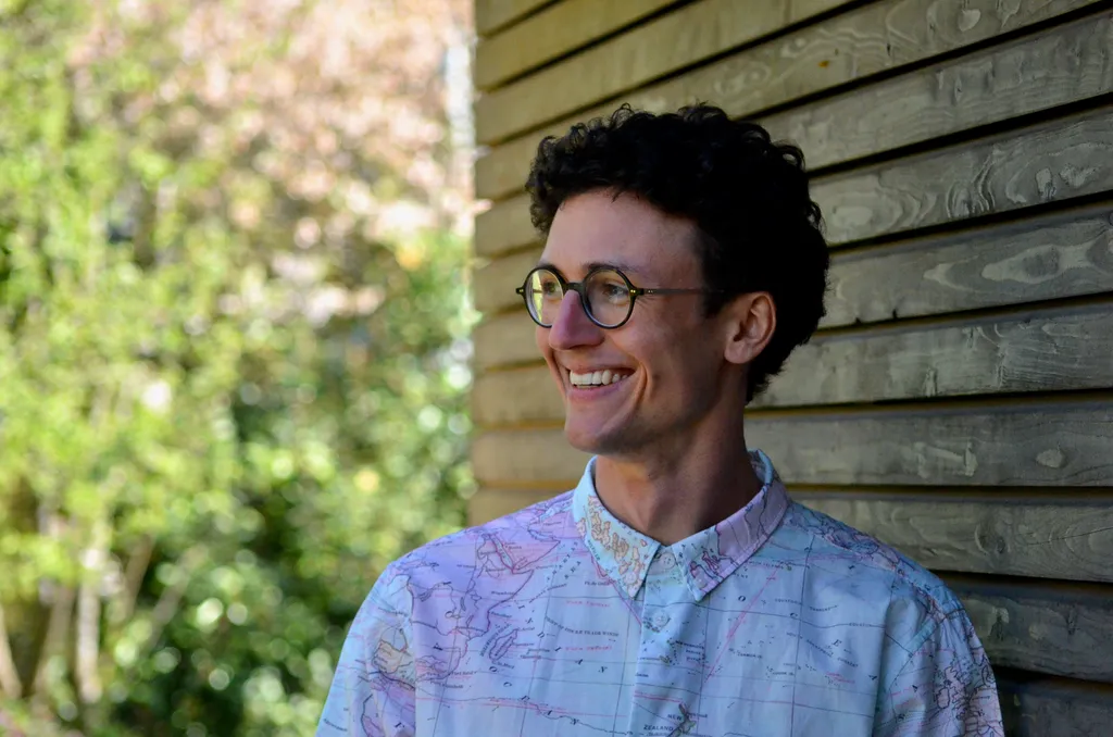 Junge Person mit Brille und farbigem Hemd.