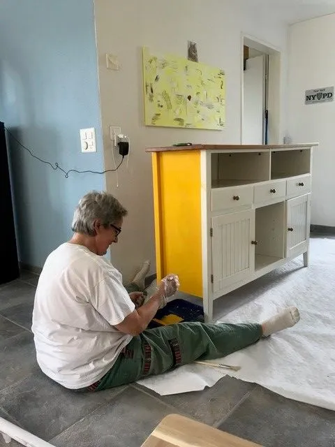 Frau streicht Schrank in gelber Farbe.