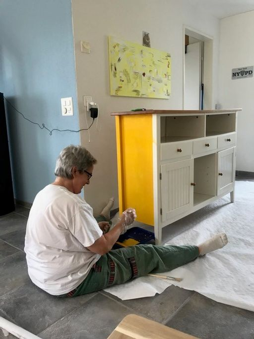 Frau streicht Schrank in gelber Farbe.