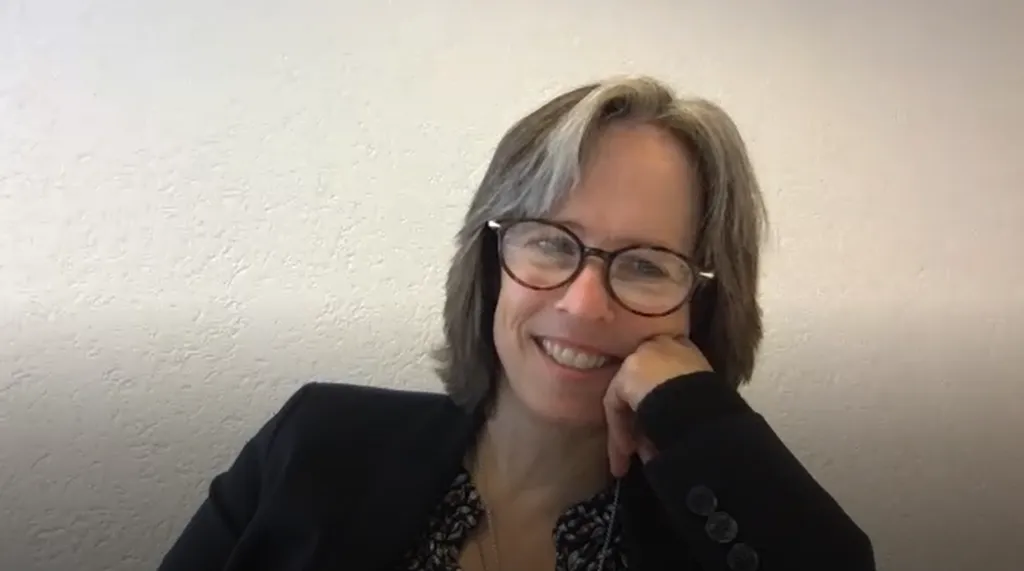 Lächelnde Person mit Brille und grauem Haar.