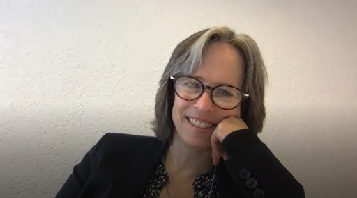 Lächelnde Person mit Brille und grauem Haar.