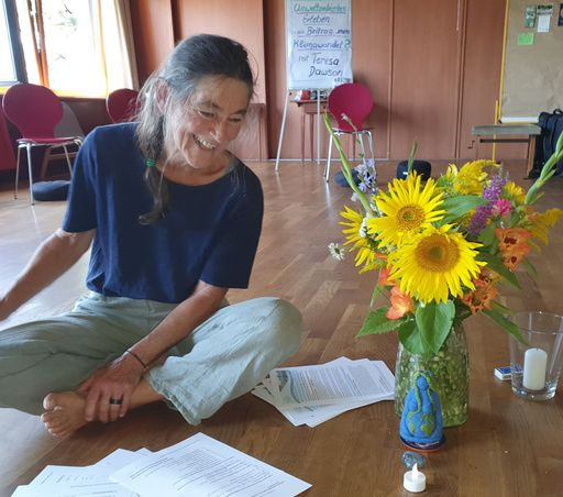 Lachende Frau sitzt auf Holzboden