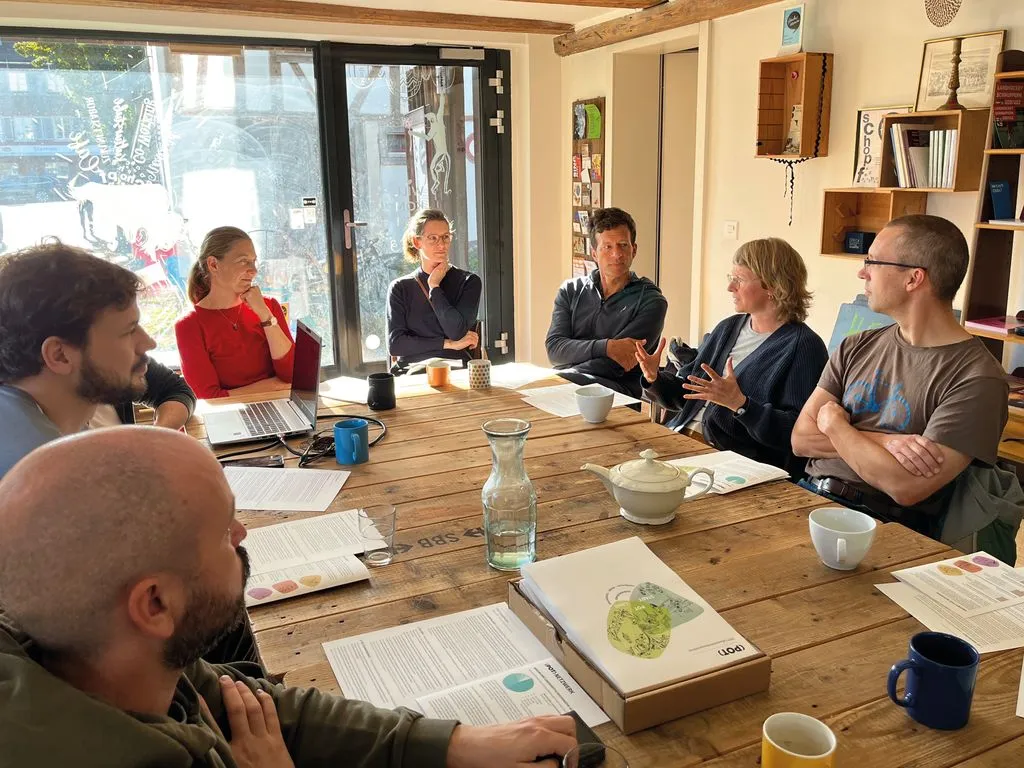 Eine Gruppe von Menschen sitzt um einen Tisch und diskutiert die Food-Coop-Gründung.