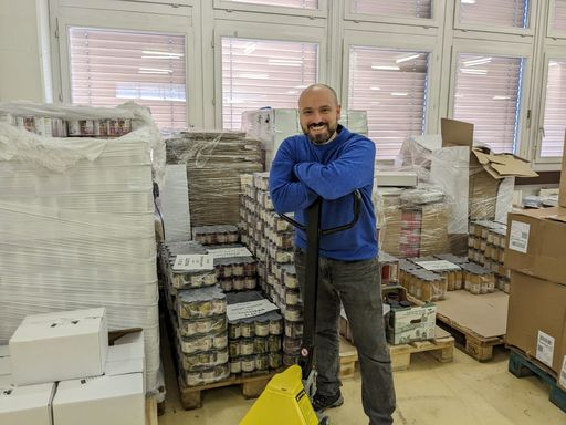 Mann steht vor Paletten mit Esswaren.