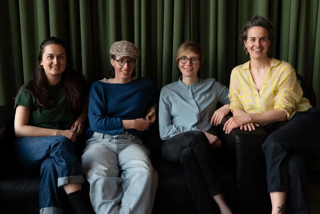 Vier junge Frauen sitzen nebeneinander.