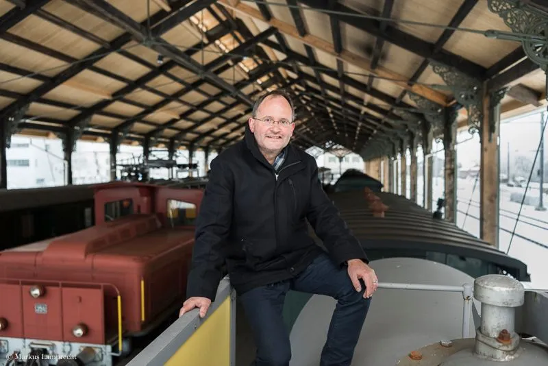 Mann sitzt auf alter Lokomotive.