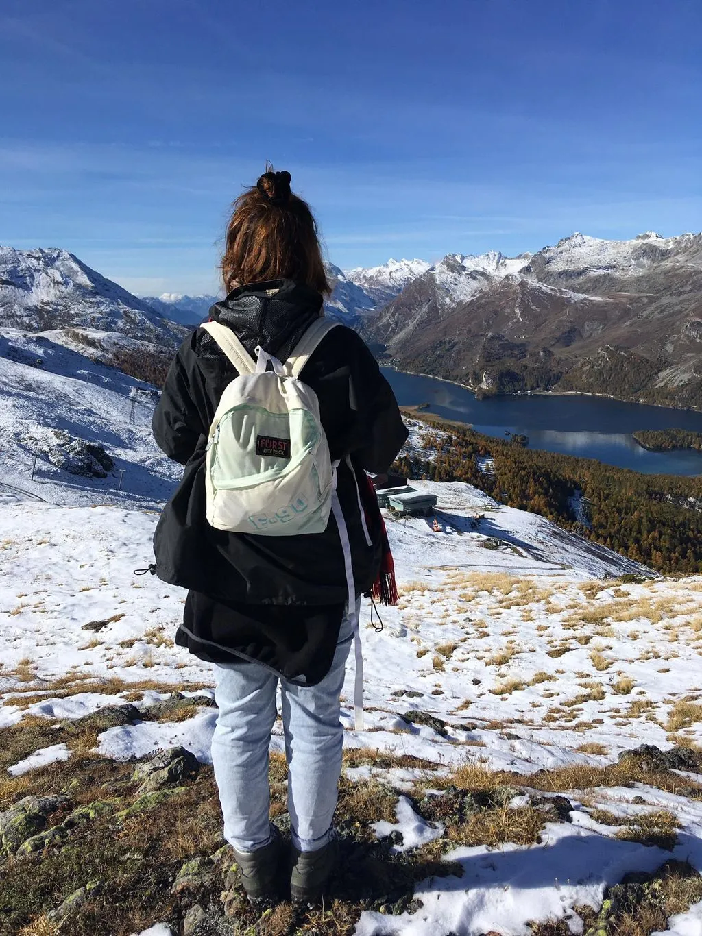 Junge Frau blickt in den Bergen in die Ferne.