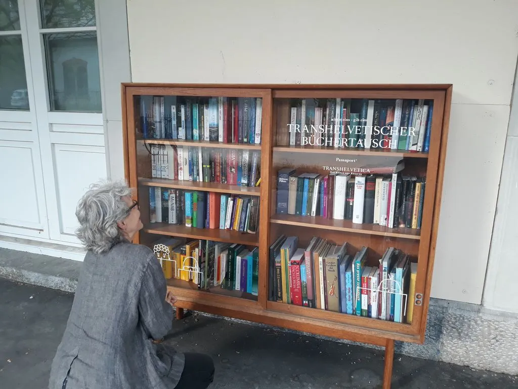 Frau kniend vor einem Bücherregal draussen