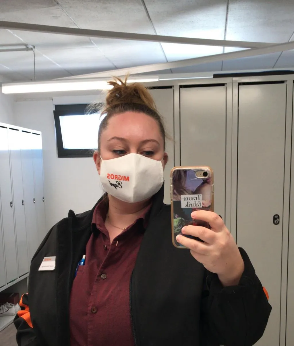 Junge Verkäuferin mit Maske macht ein Selfie vor Spiegel