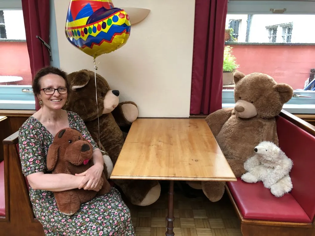 Eine Frau sitzt mit Plüschtieren an einem Restauranttisch.