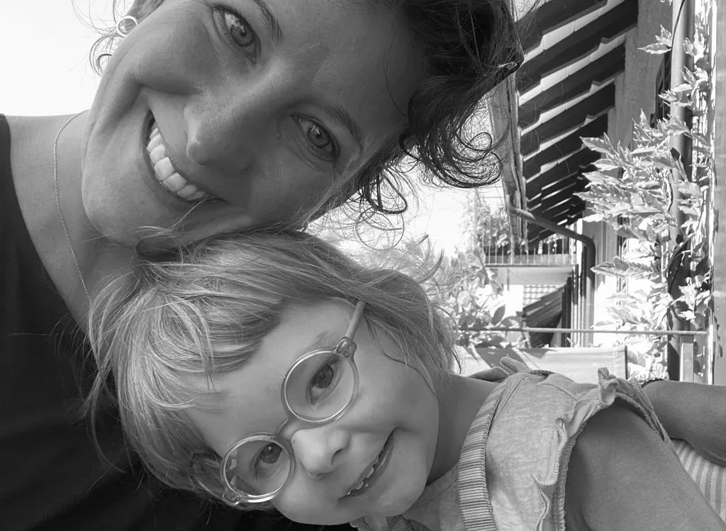 Frau mit kleinem Kind auf Balkon.