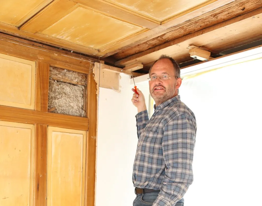 Mann renoviert alte Holzdecke