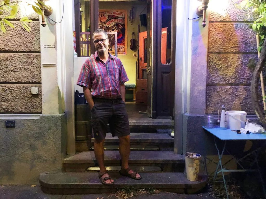 Mann in Sandalen steht vor Bar