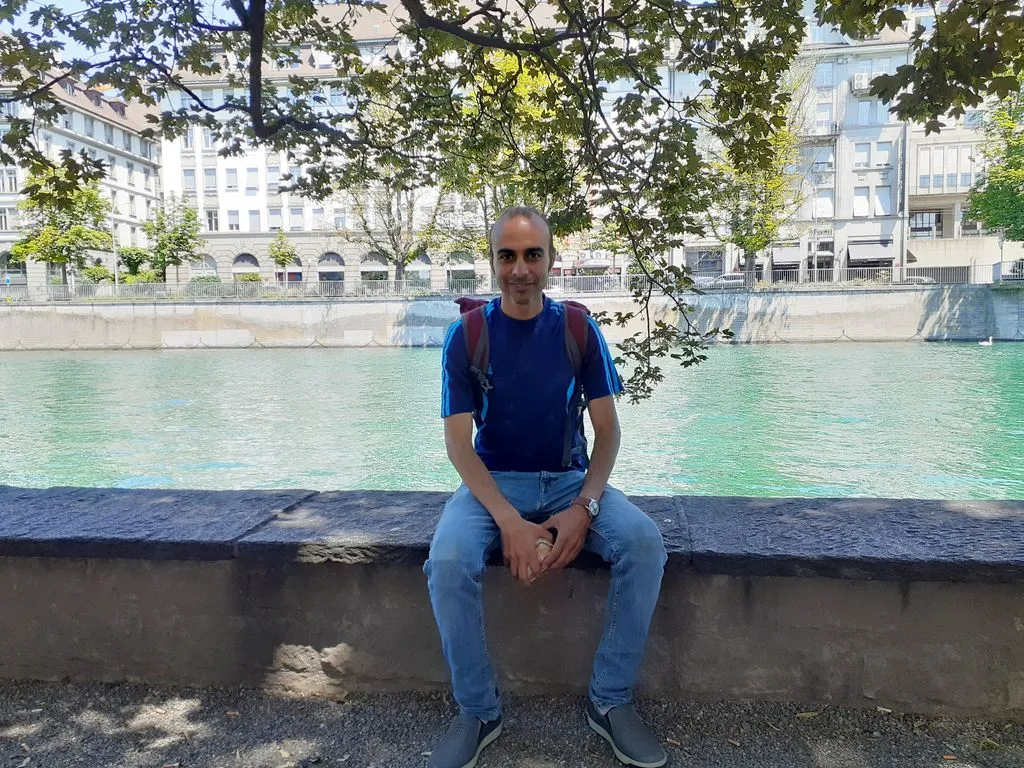 Mann sitzt auf Steinmauer vor Fluss in der Stadt.