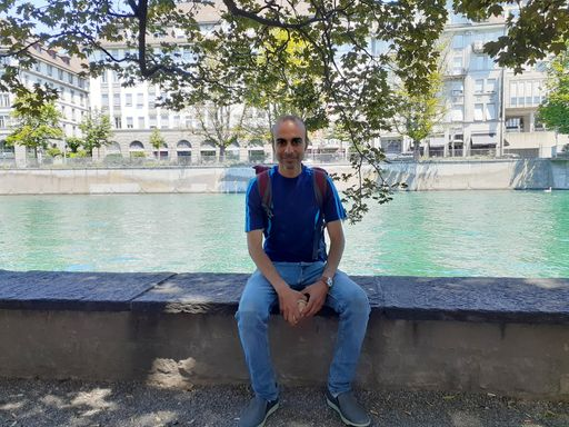 Mann sitzt auf Steinmauer vor Fluss in der Stadt.