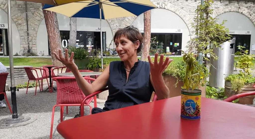 Eine Frau diskutiert in einem Cafe bei Sonnenschein.