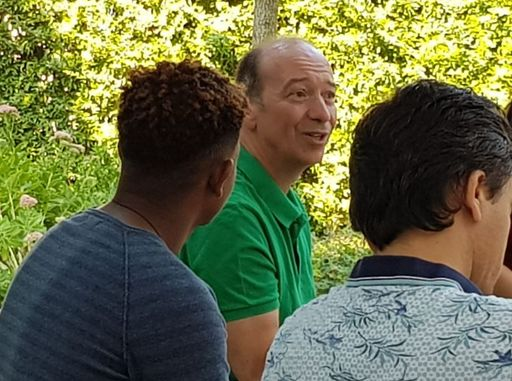 Lehrer spricht, Gruppe sitzt in Kreis.