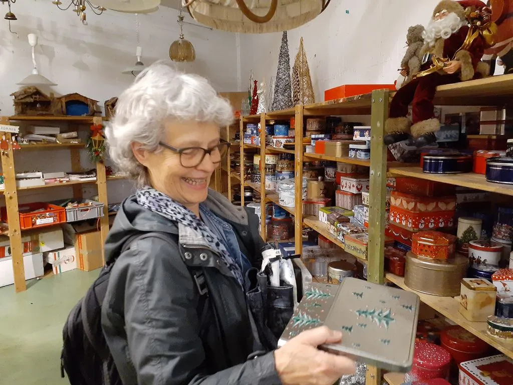 Frau in einem Brockenhaus schaut alte Büchse an