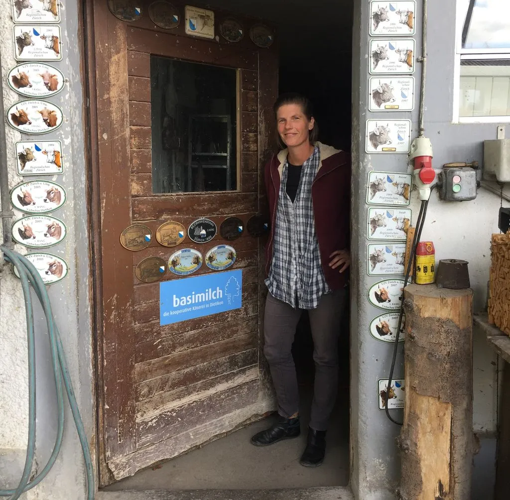 Frau steht in der Türe eines alten Bauernhauses