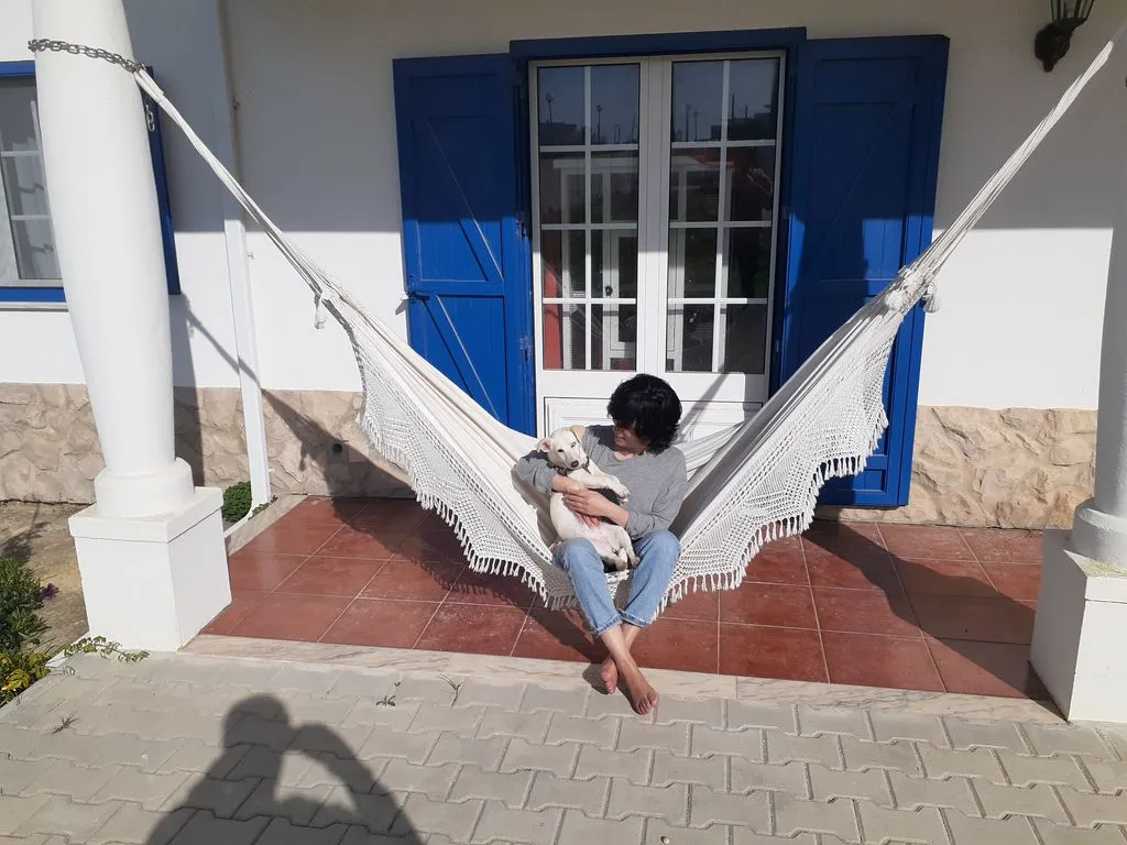 Frau sitzt mit Hund in Hängematte