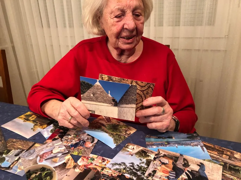 Ältere Frau schaut einen Stapel an alten Postkarten durch