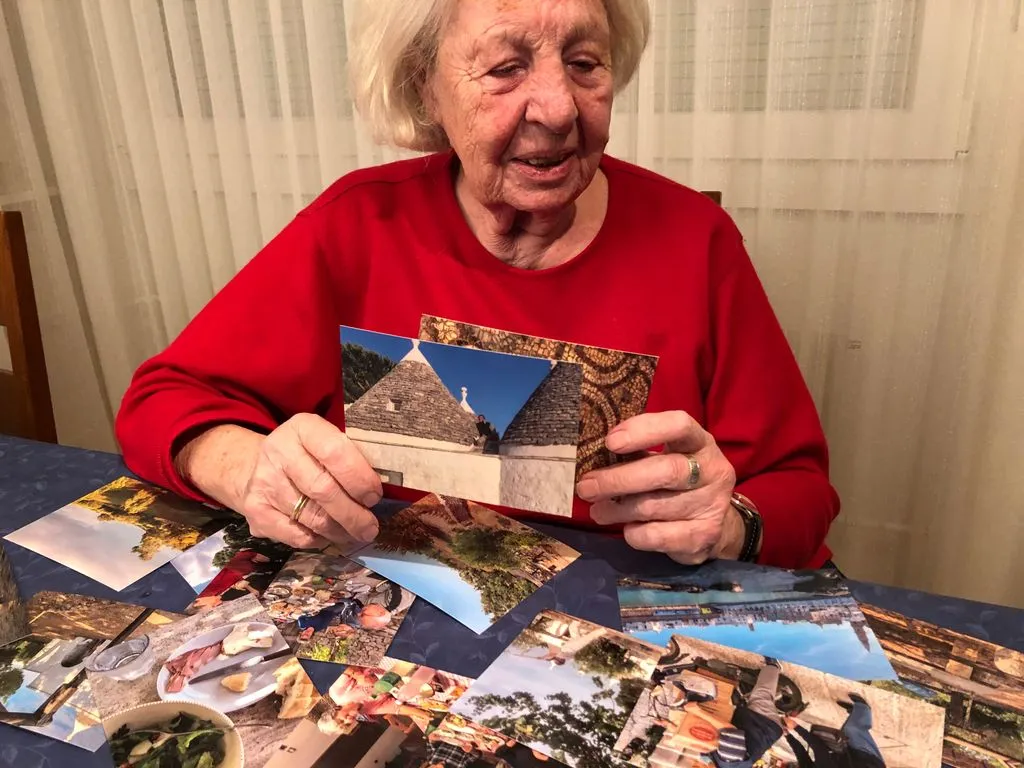 Ältere Frau schaut einen Stapel an alten Postkarten durch