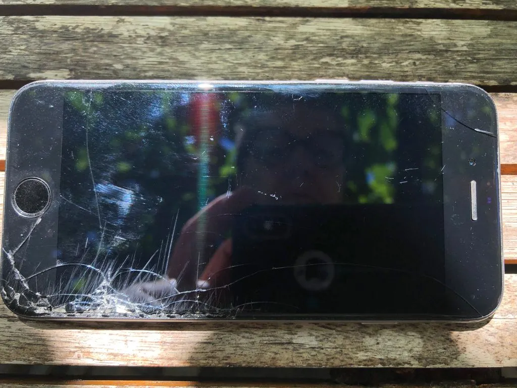 Reflektion einer Frau in einem Smartphone mit zerbrochenem Display