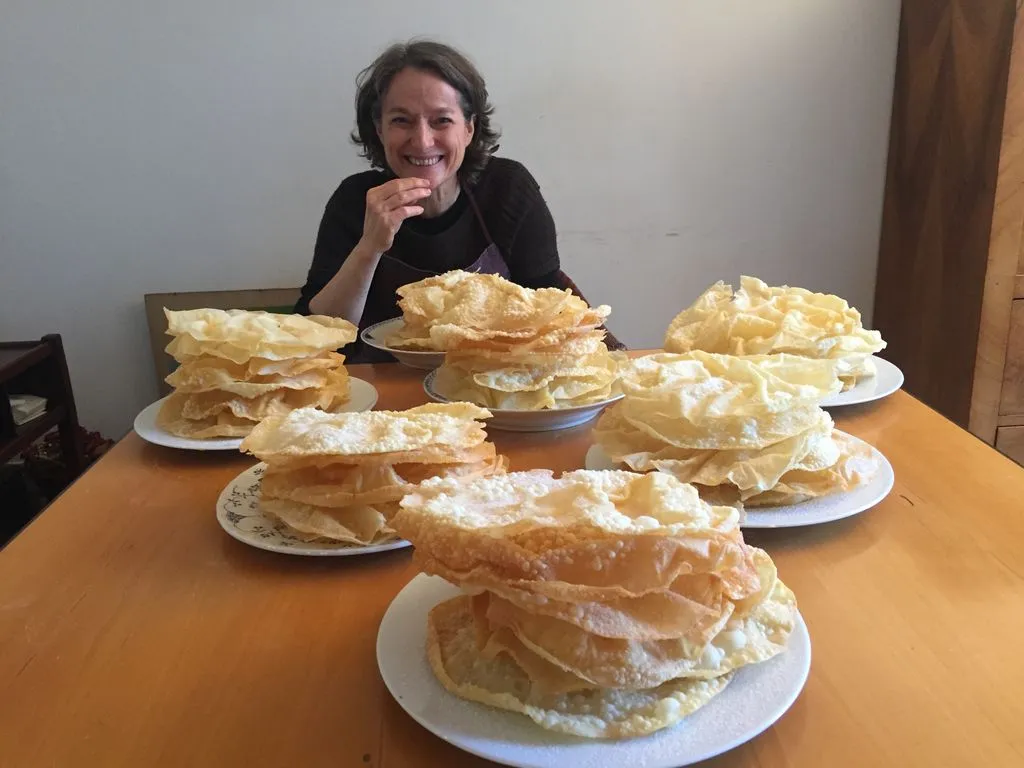 Frau hinter Tellern voller goldbrauner Fasnachtschüechli