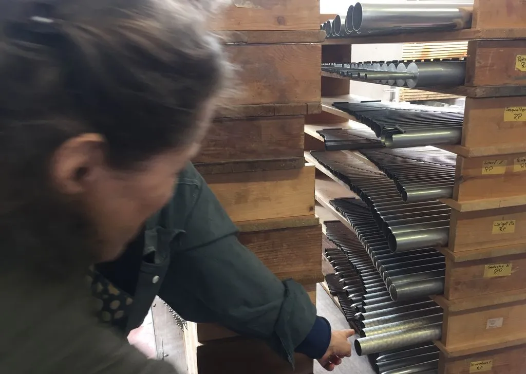 Person inspiziert Orgelpfeifen.