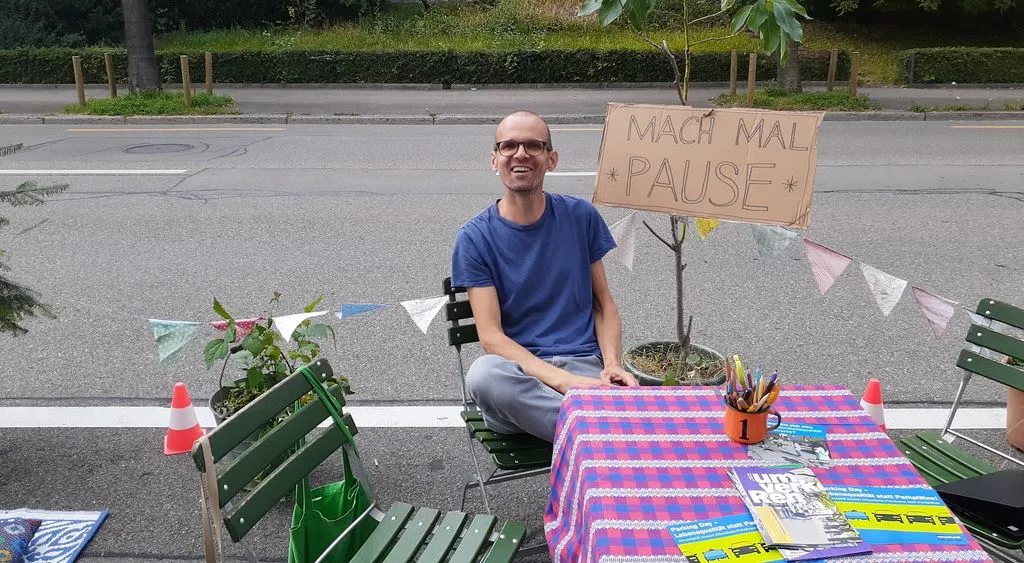 Mann sitzt auf Stuhl auf Parkplatz