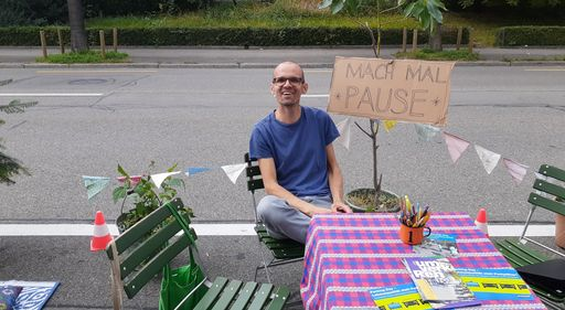 Mann sitzt auf Stuhl auf Parkplatz.