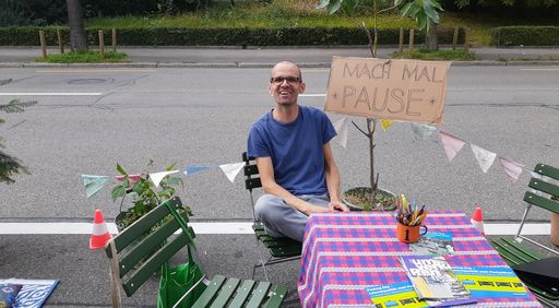 Mann sitzt auf Stuhl auf Parkplatz