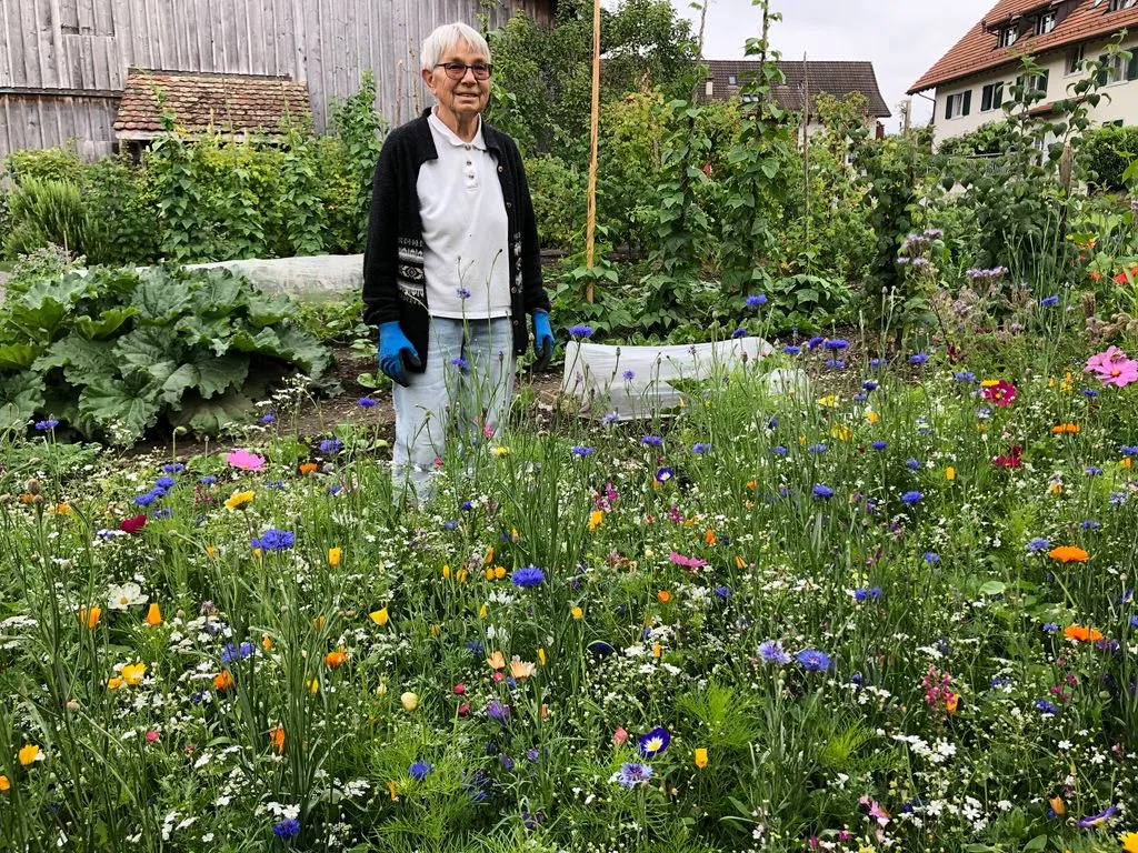Seniorin steht inmitten Blumenwiese