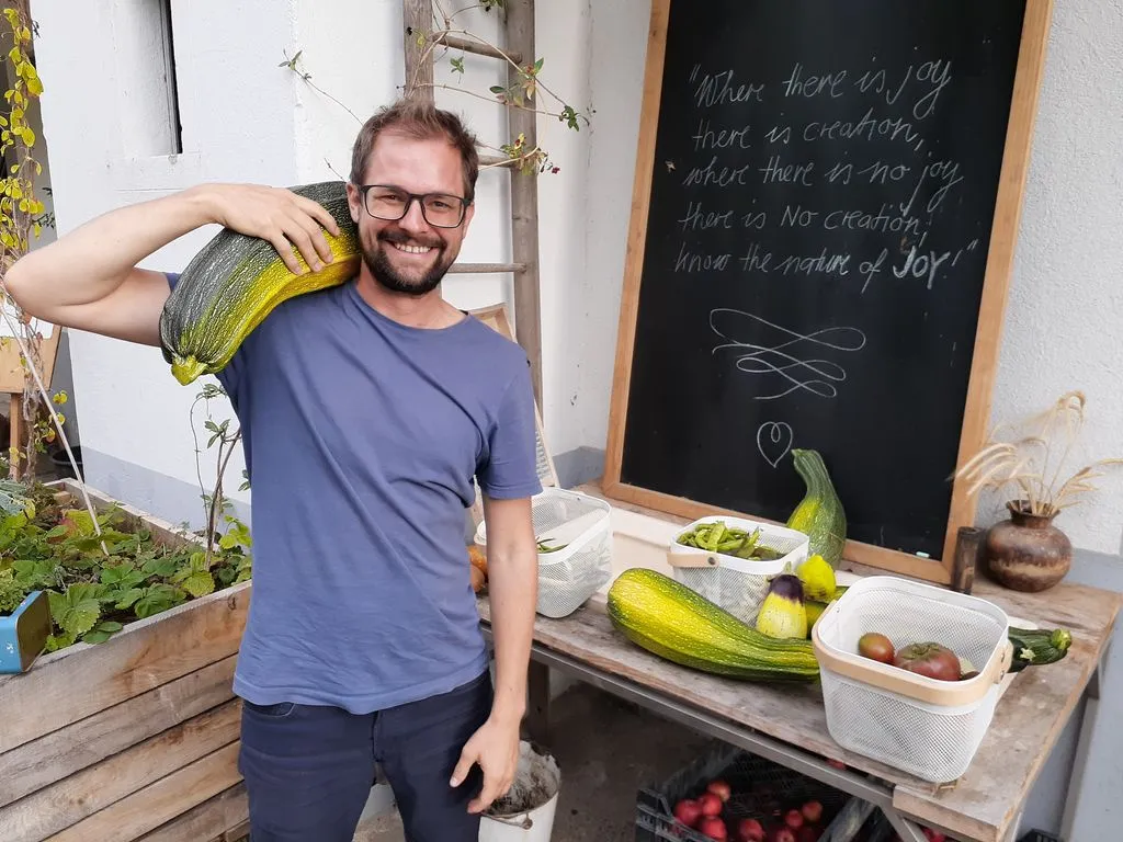 Lachender Mann mit grosser Zucchetti auf Schulter